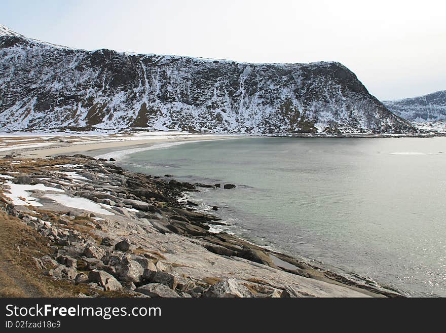 Rocks and snowy mountains of Haukland beach, Lofoten islands. Rocks and snowy mountains of Haukland beach, Lofoten islands