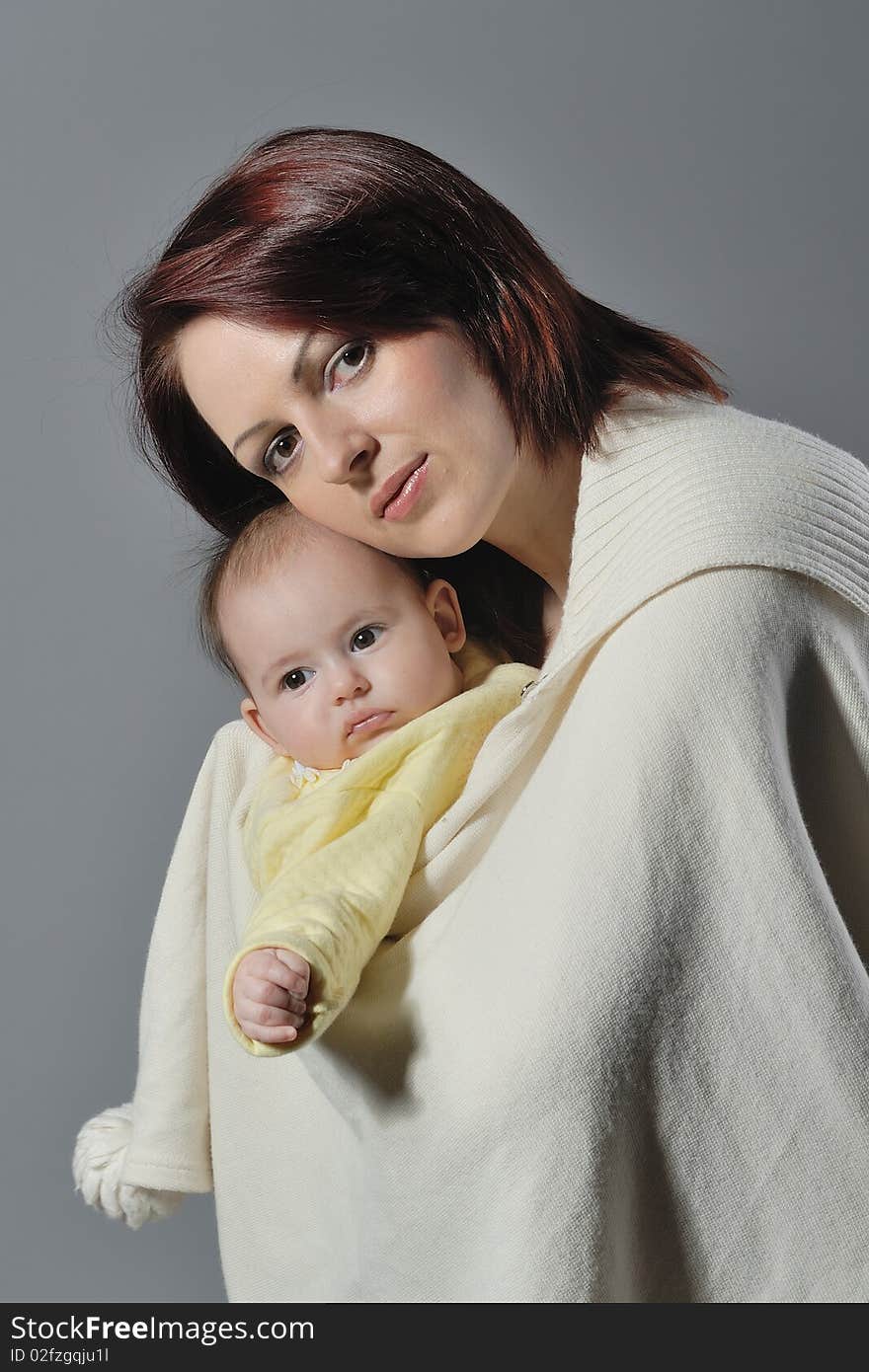 Child in mother arms on grey background