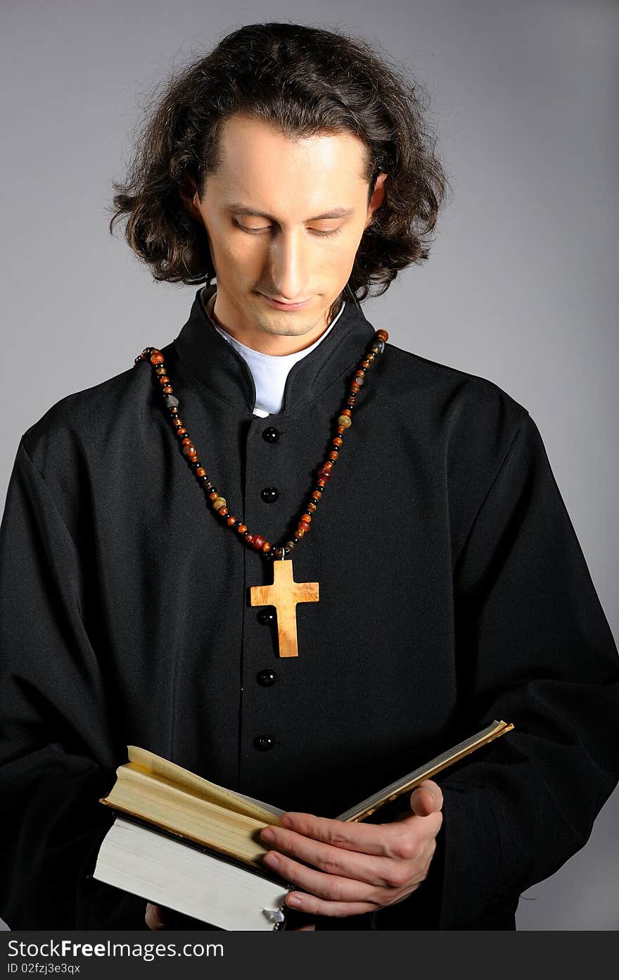 Conceptual portrait of Praying priest with wooden cross reading Holy Bible. yellow background. Conceptual portrait of Praying priest with wooden cross reading Holy Bible. yellow background