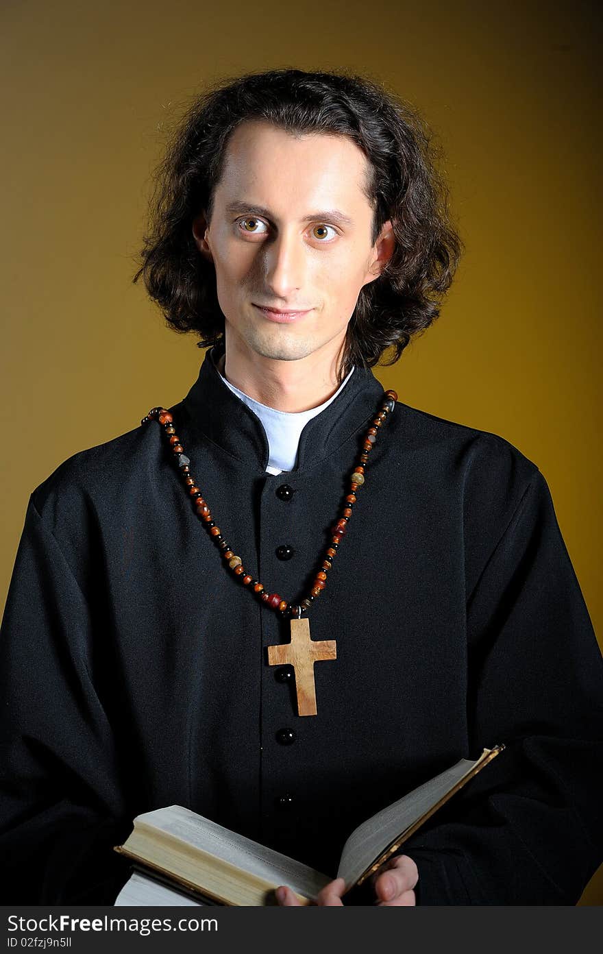 Praying priest with wooden cross and Bible