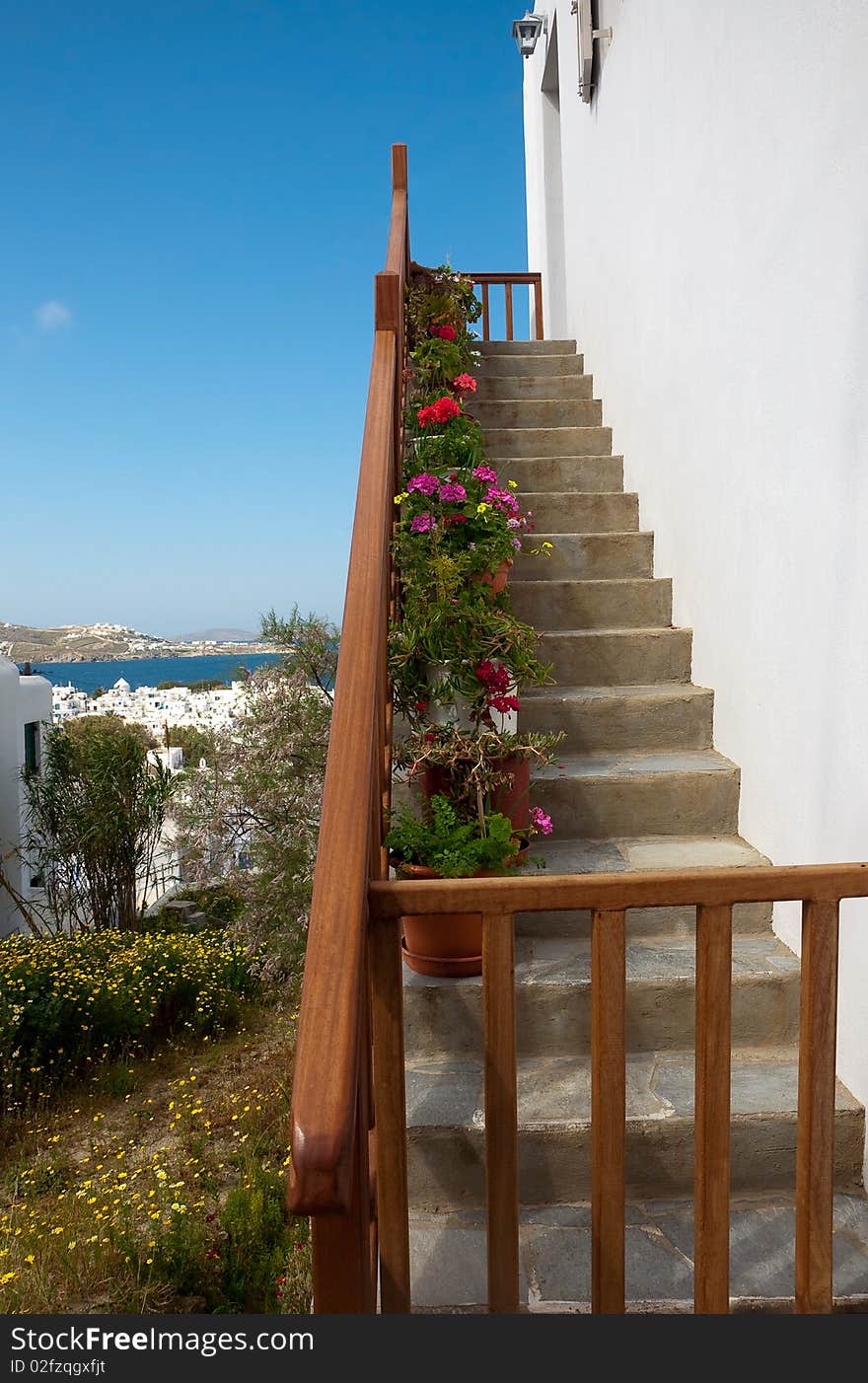 Stairs with flowers in pots on a background choir of Mykonos and greens