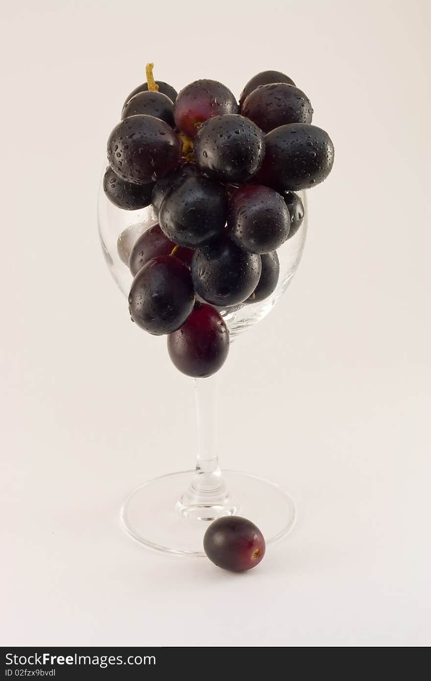 Grapes cluster in water drops in a glass on a white background