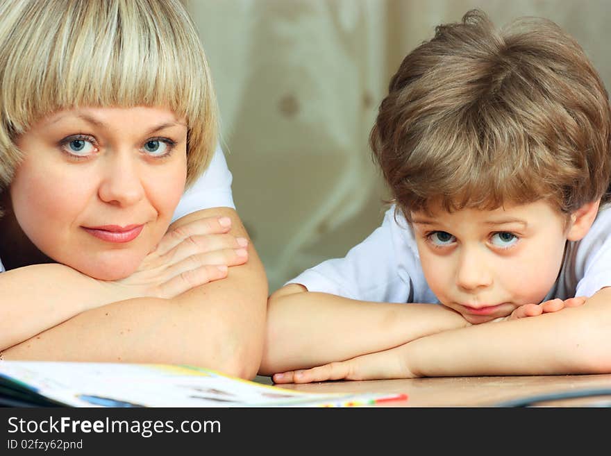 Woman and little boy lying down on the floor and reading a book. Woman and little boy lying down on the floor and reading a book