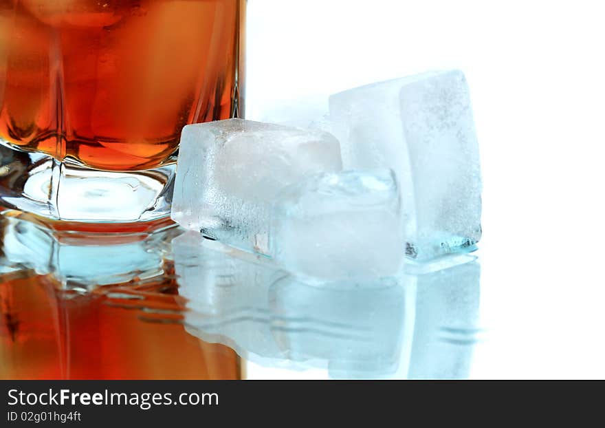 Glass of whiskey with ice cubes on white background with reverberation