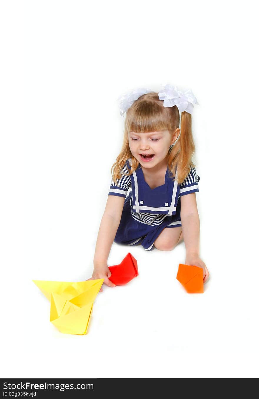 Cute young girl in sailor dress with paper ships over white. Cute young girl in sailor dress with paper ships over white