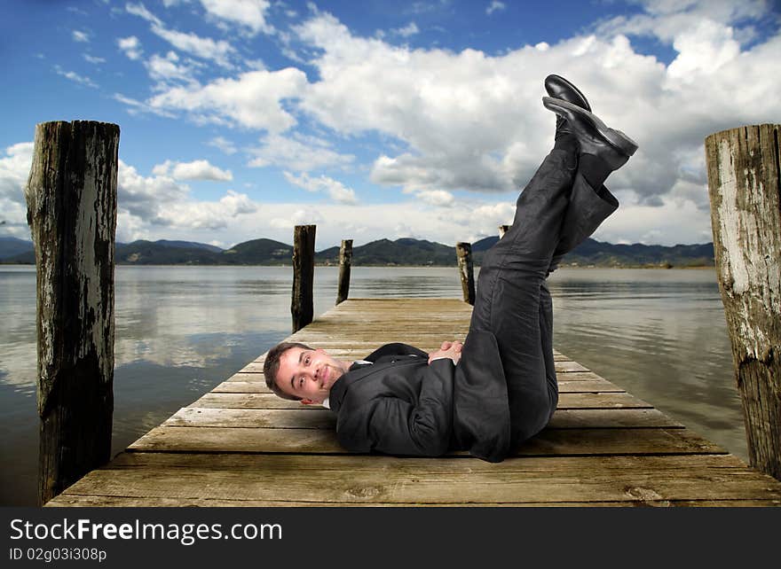 Businessman lying upright on a dock. Businessman lying upright on a dock