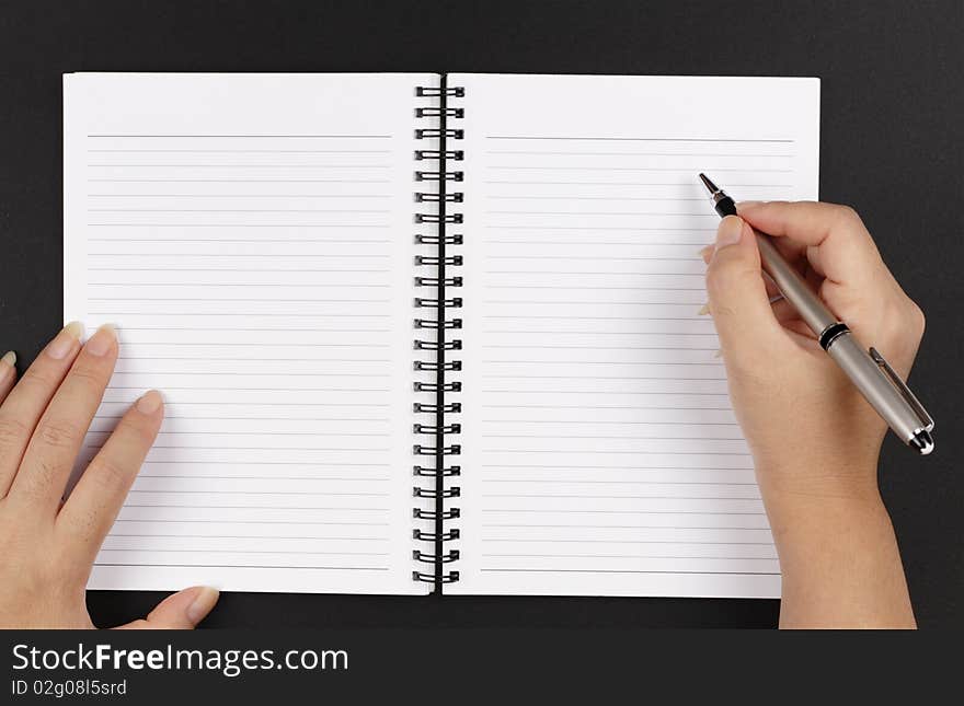 A pair of hands, a pen and a notebook on a black background. A pair of hands, a pen and a notebook on a black background