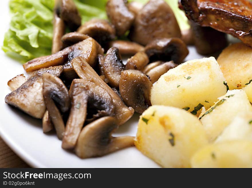 Tasty grilled food, chicken meat, roasted potatoes and mushrooms and sallet