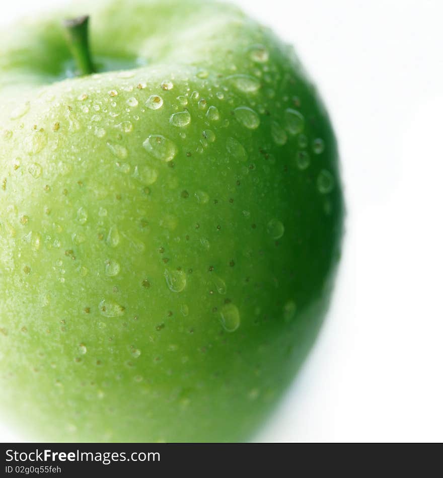 Green apple with drops of water on a white background