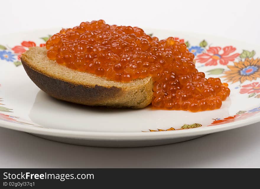 Red caviar on a piece of black bread on a white background