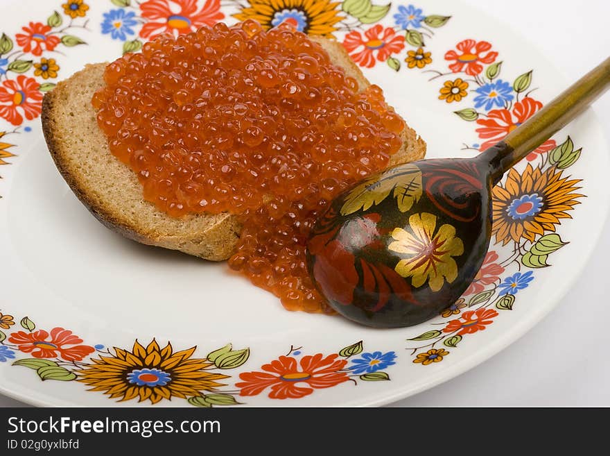 Red caviar on a piece of black bread on a white background