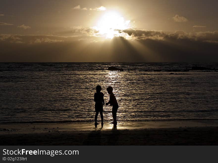 Two children on the beach at sunset