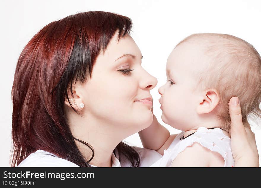 Cute baby trying to kiss her mother. Closeup portrait.