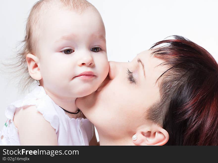 Young beautiful mother kissing cute curious baby, family portrait. Young beautiful mother kissing cute curious baby, family portrait