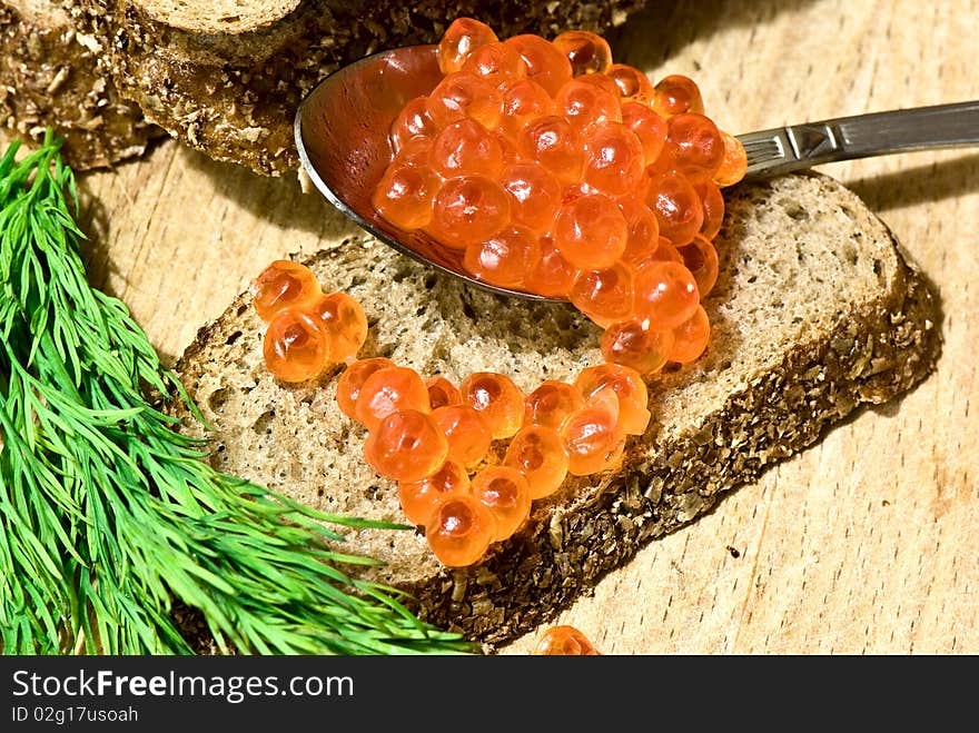 Red caviar in a spoon on a slice of rye bread. Red caviar in a spoon on a slice of rye bread