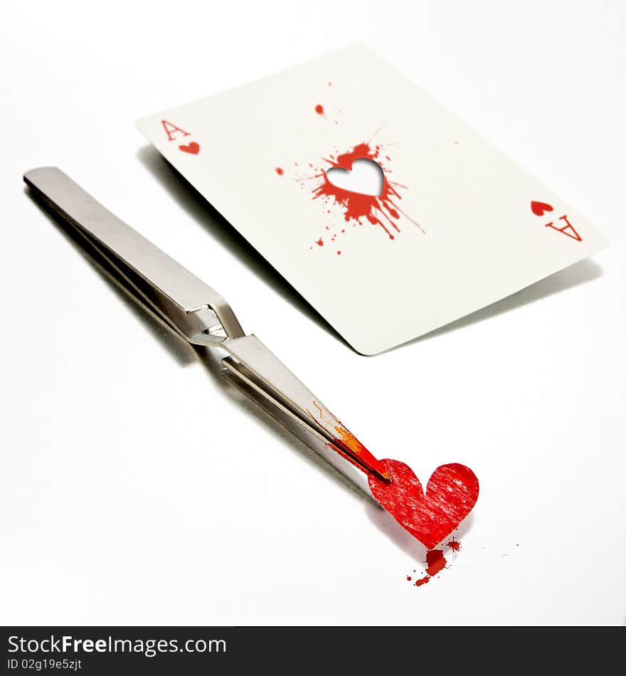 Some tweezers holding a paper heart, just removed from an ace of hearts. Some tweezers holding a paper heart, just removed from an ace of hearts.