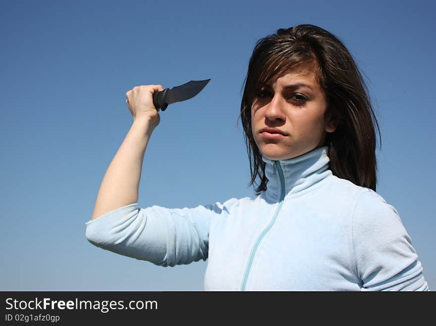 A girl with a knife in a hand isolated on blue background