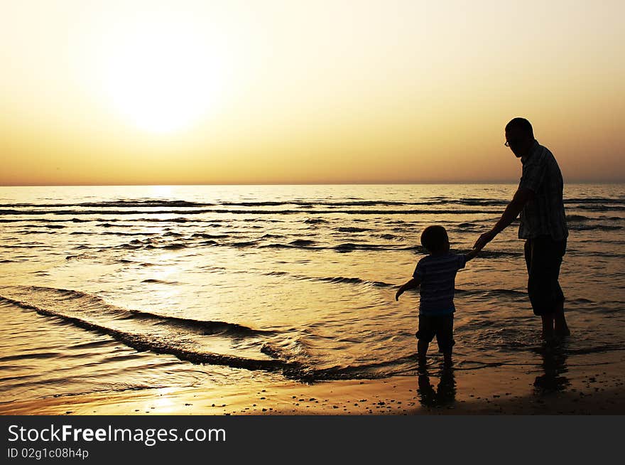 Child with his father at sea. Sunset