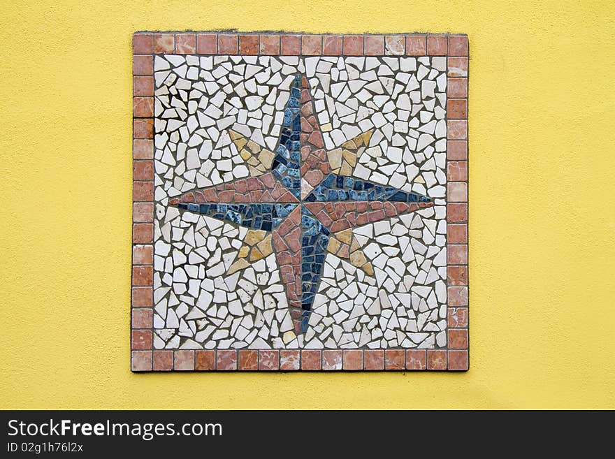 Mosaic compass rose on a yellow wall