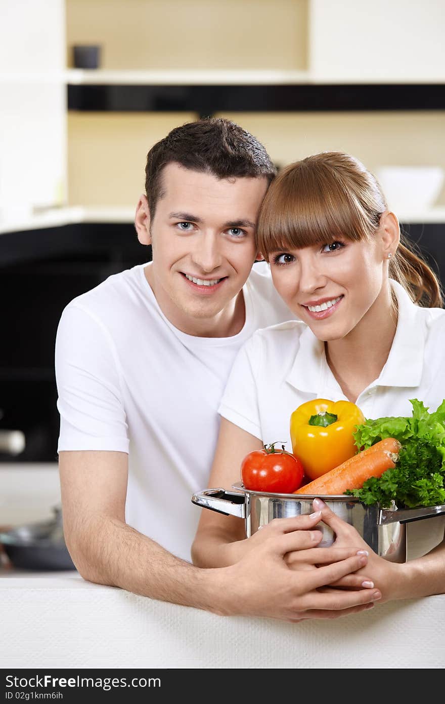 Young couple with capacity with vegetables in the foreground. Young couple with capacity with vegetables in the foreground