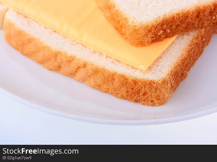 On a plate two slices of bread, between them cheese.