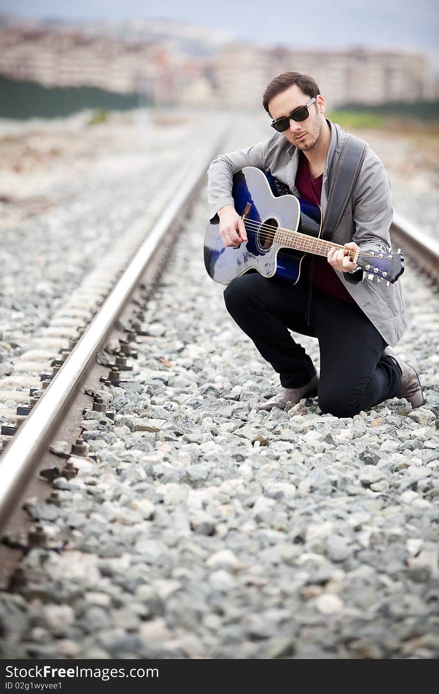 Young handsome musician playing his blue guitar.