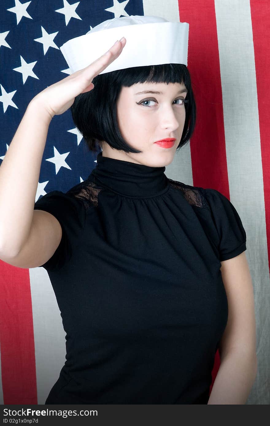 Young woman saluting in sailor cap with american flag. Young woman saluting in sailor cap with american flag