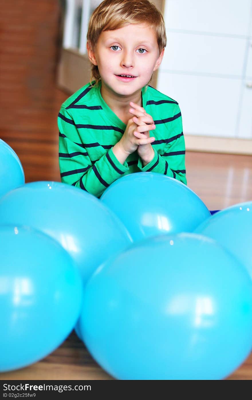 Happy boy sitting with blue  balloons on the wooden floor. Happy boy sitting with blue  balloons on the wooden floor