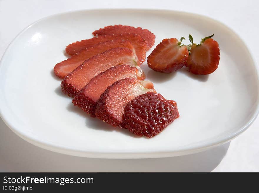 Cut strawberry on white plate. Cut strawberry on white plate