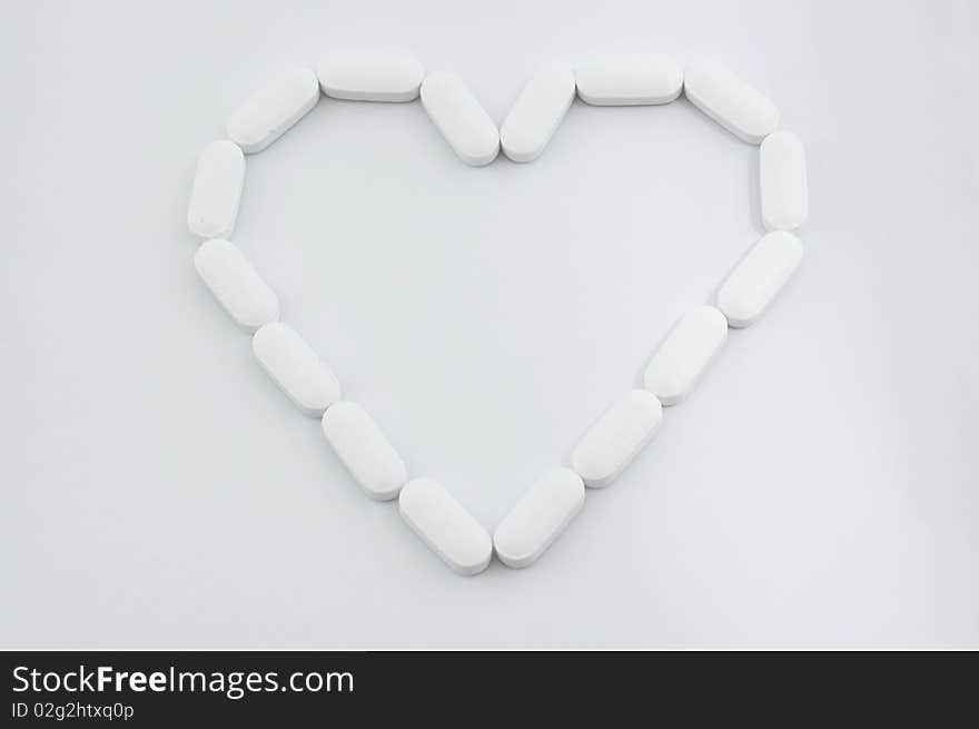 White pills in heart shape isolated on white background. White pills in heart shape isolated on white background.