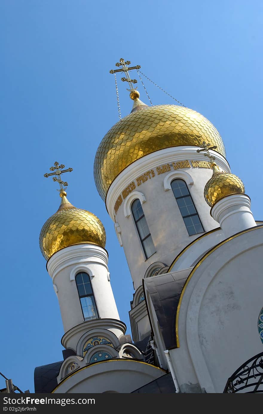 Gold domes of Orthodox Church with crosses in spring. White Romanesque building with frescos. Odessa