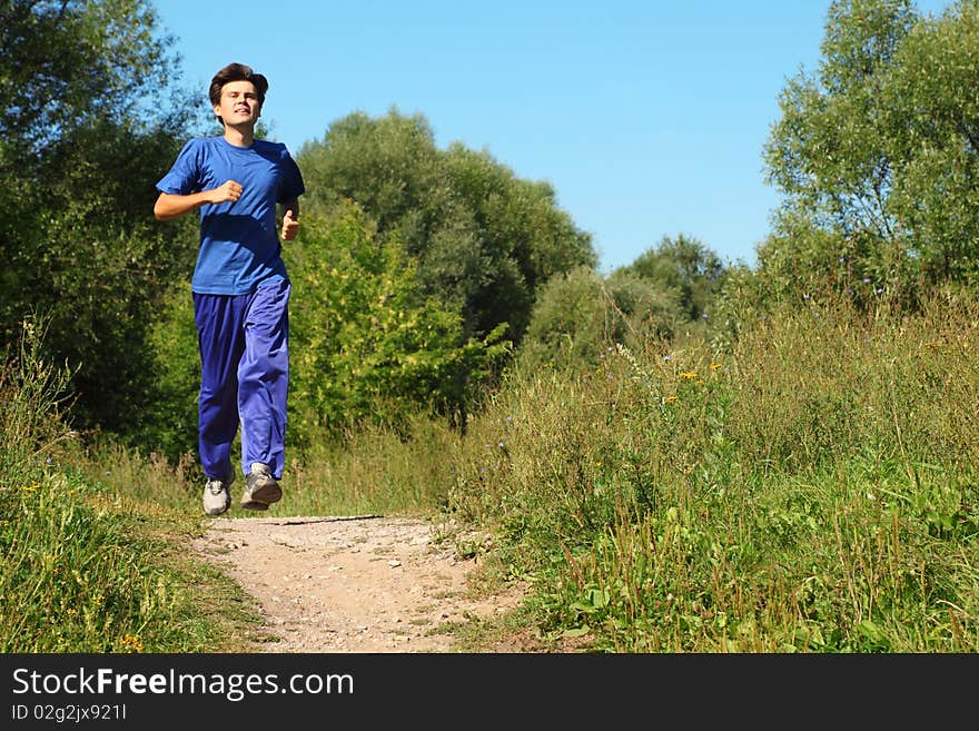 Man wearing sporty clothes is running along path