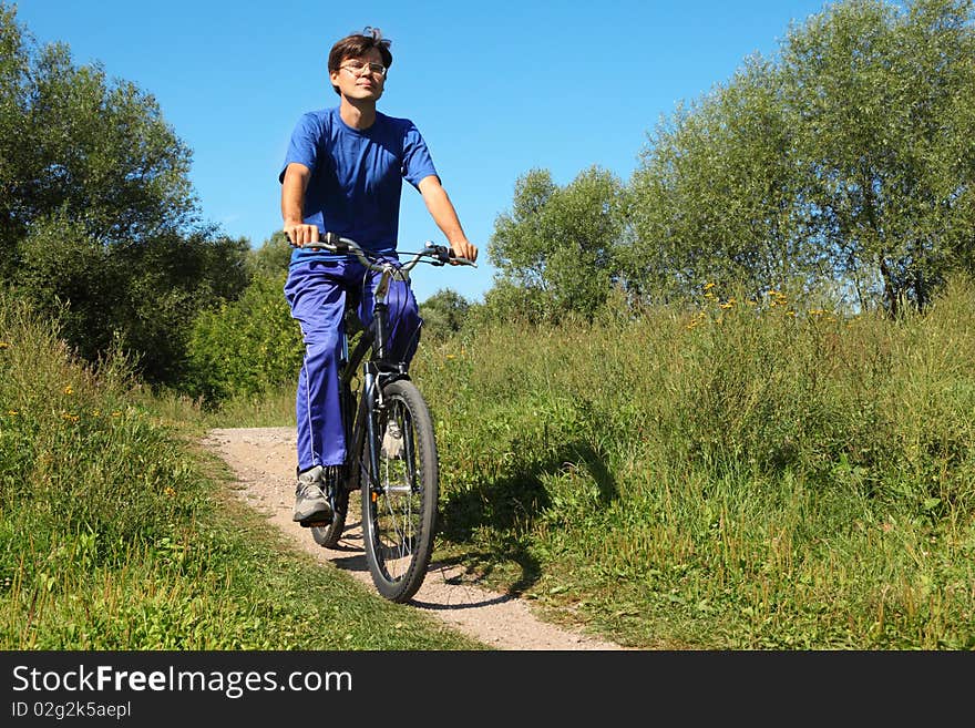 One man wearing sporty clothes is riding on a bycicle and looking at camera. sunny summer day. One man wearing sporty clothes is riding on a bycicle and looking at camera. sunny summer day.