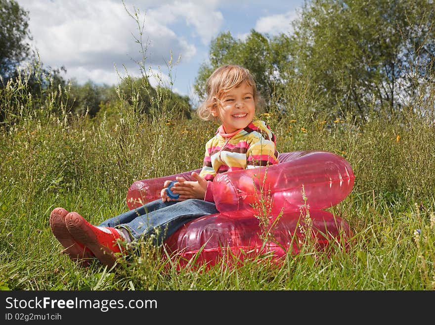 Young girl in summer day rest in the open air sitting on an inflatable armchair. Young girl in summer day rest in the open air sitting on an inflatable armchair