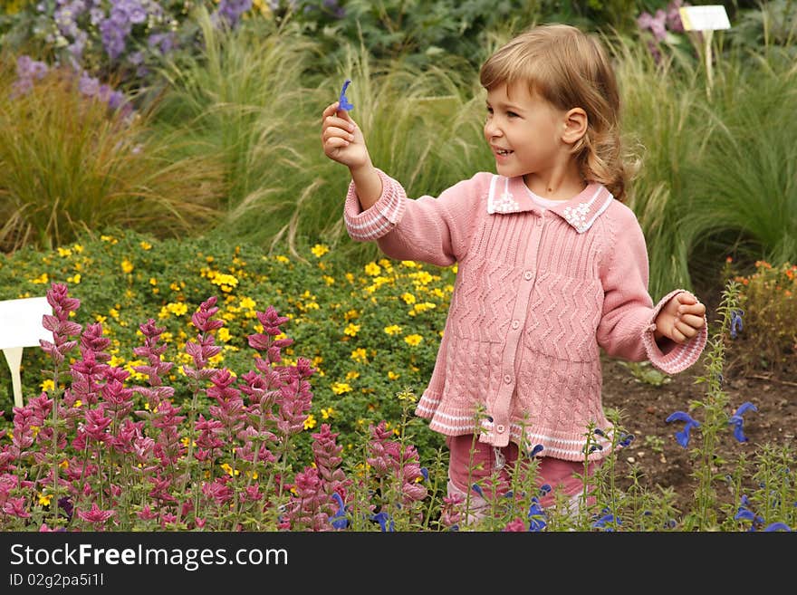 Young girl holding in her hand annual delphinium, pink around salvia