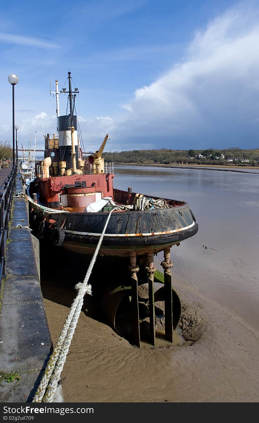 Old tug boat moored by a river bank. Old tug boat moored by a river bank.