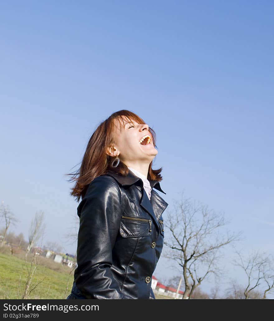 Photo if a girl loudly laughing on the blue sky background. Photo if a girl loudly laughing on the blue sky background