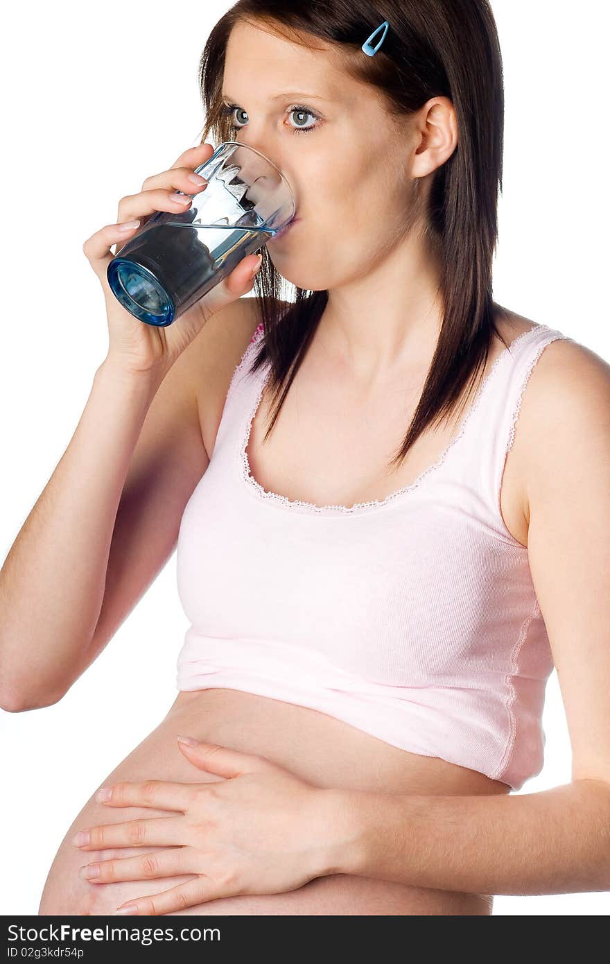 Thirsty pregnant girl drinking water with one hand on her belly