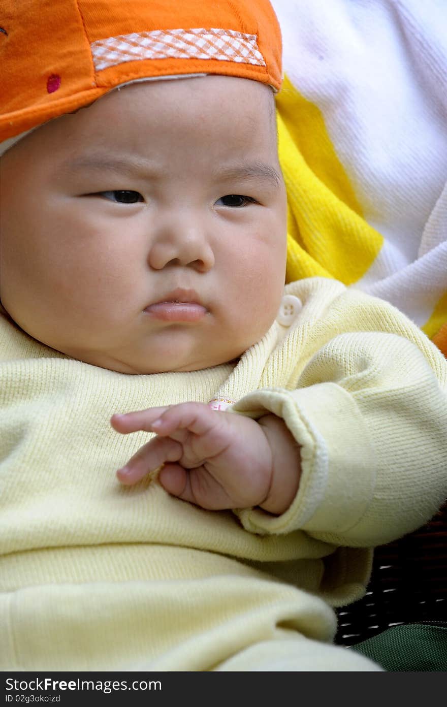 A cute baby with a orange cap.