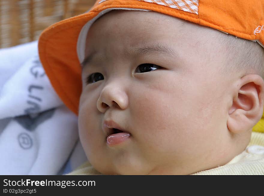 A cute baby with a orange cap.