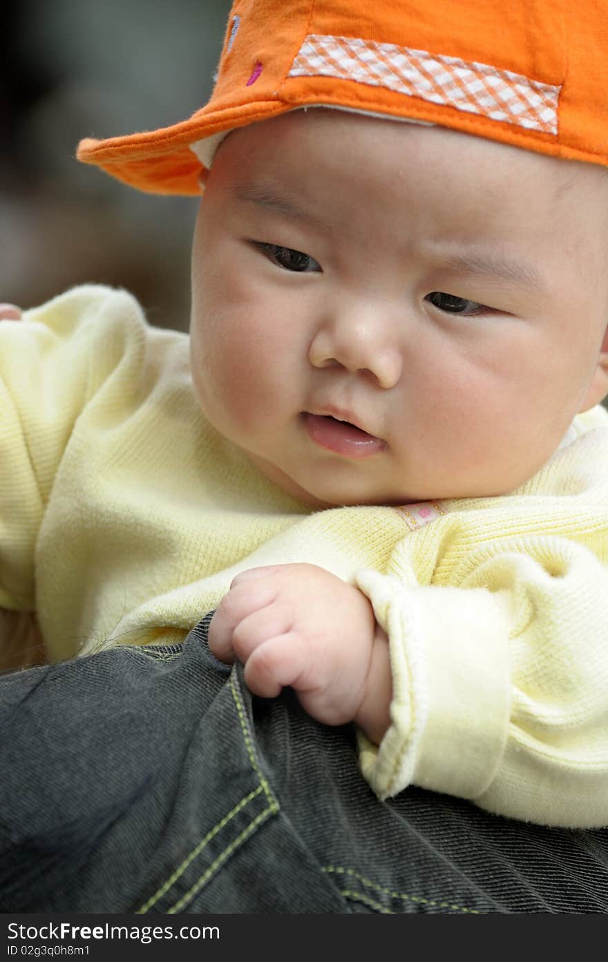 A cute baby with a orange cap.