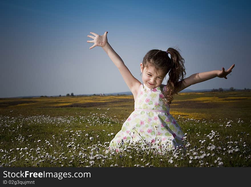 Little girl sitting in white flowers with her hands in the air. Little girl sitting in white flowers with her hands in the air