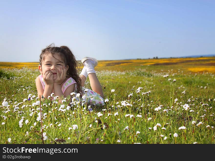 Little girl sitting in a field of white flowers