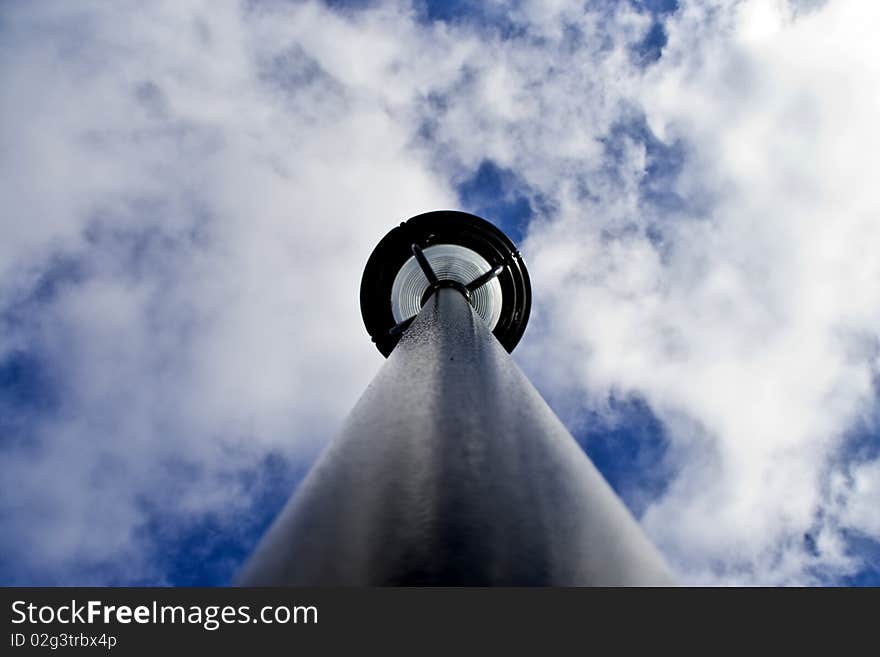 A photograph of a light pole from an uncommon perspective, looking straight up the pole.  There is a saturated blue sky background with bellowing white clouds.  The photograph was taken on a brisk clear winter day. A photograph of a light pole from an uncommon perspective, looking straight up the pole.  There is a saturated blue sky background with bellowing white clouds.  The photograph was taken on a brisk clear winter day.