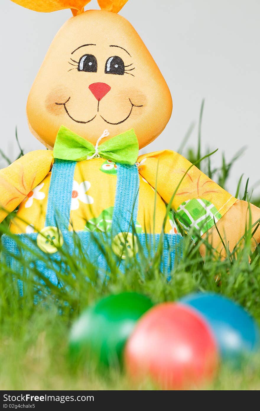 Toy easter bunny with colored eggs in the grass