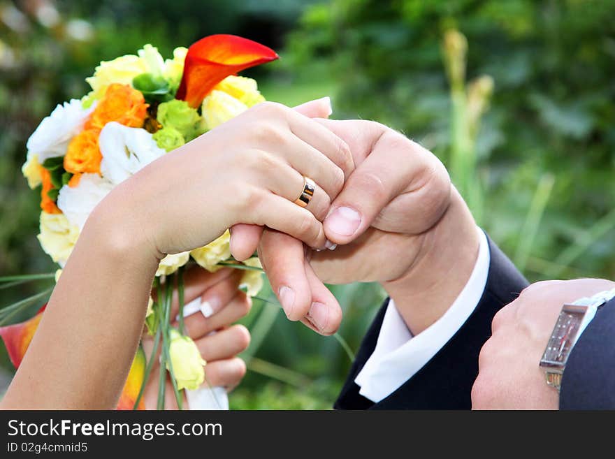 Newlywed couple holding hands over bouquet of flowers. Newlywed couple holding hands over bouquet of flowers.