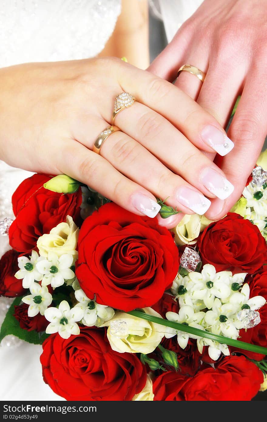 Newlywed couple holding hands over bouquet of flowers. Newlywed couple holding hands over bouquet of flowers.