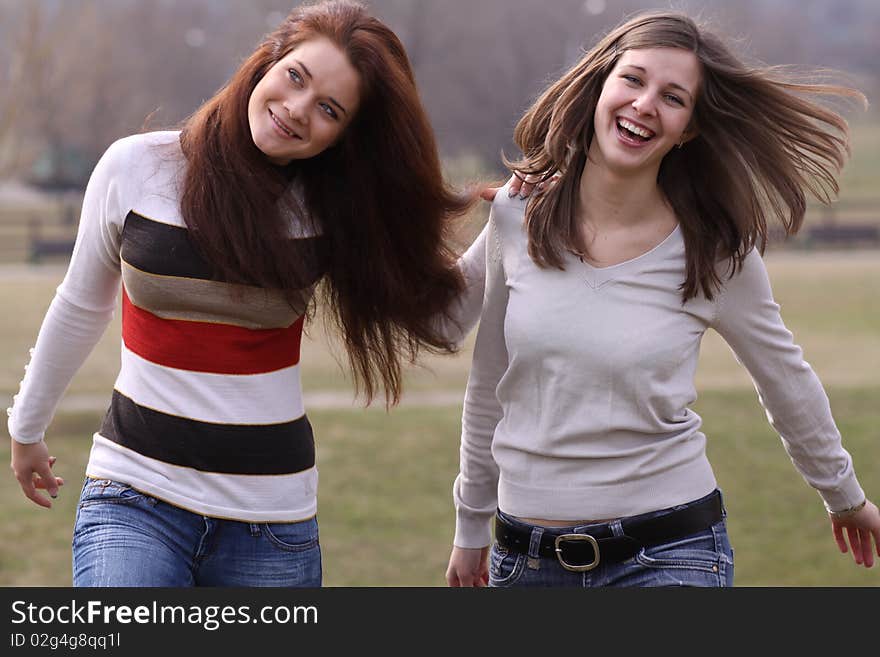 Two cheerful walking girls in the park. Two cheerful walking girls in the park