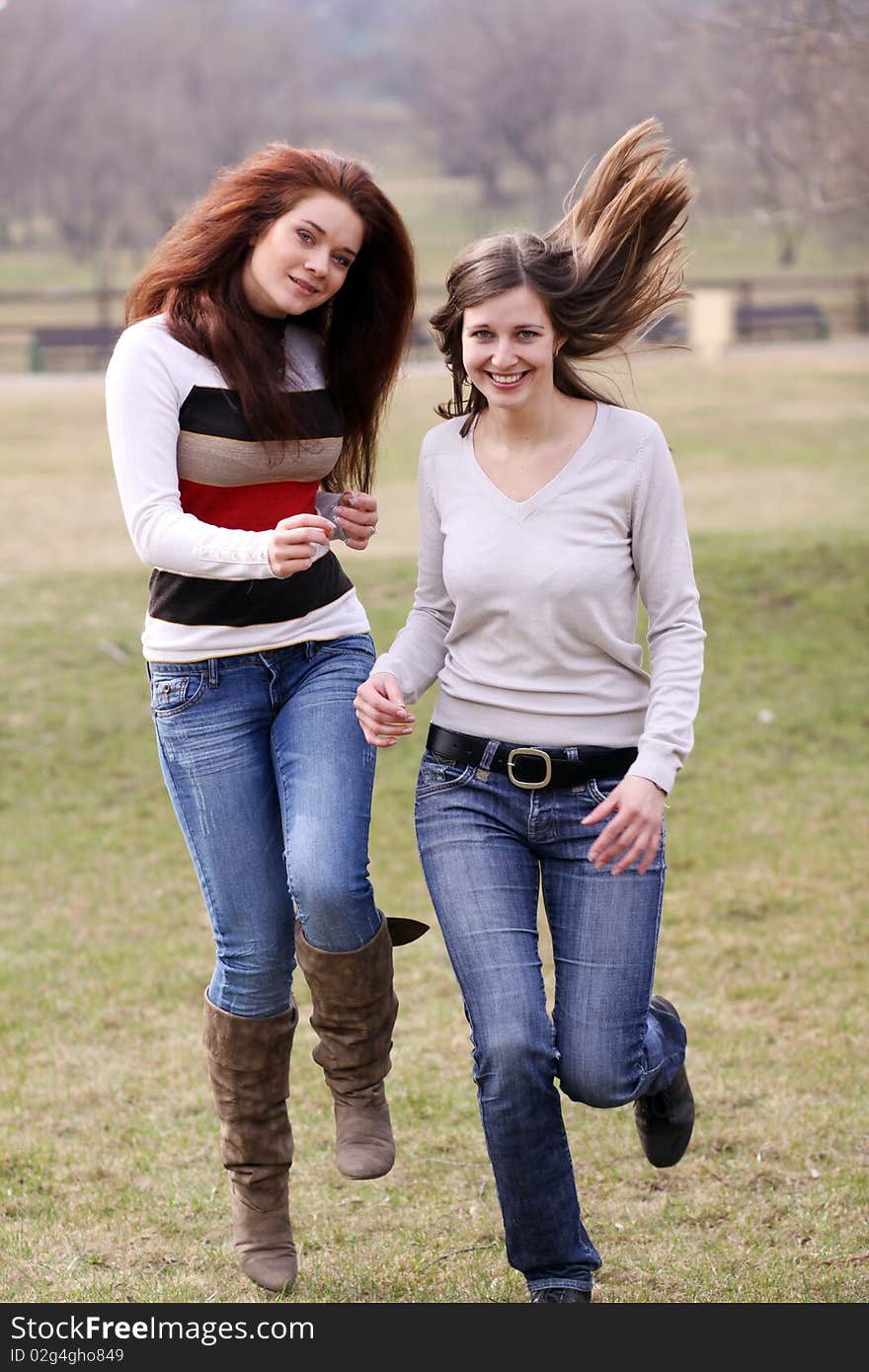 Two cheerful walking girls in the park. Two cheerful walking girls in the park