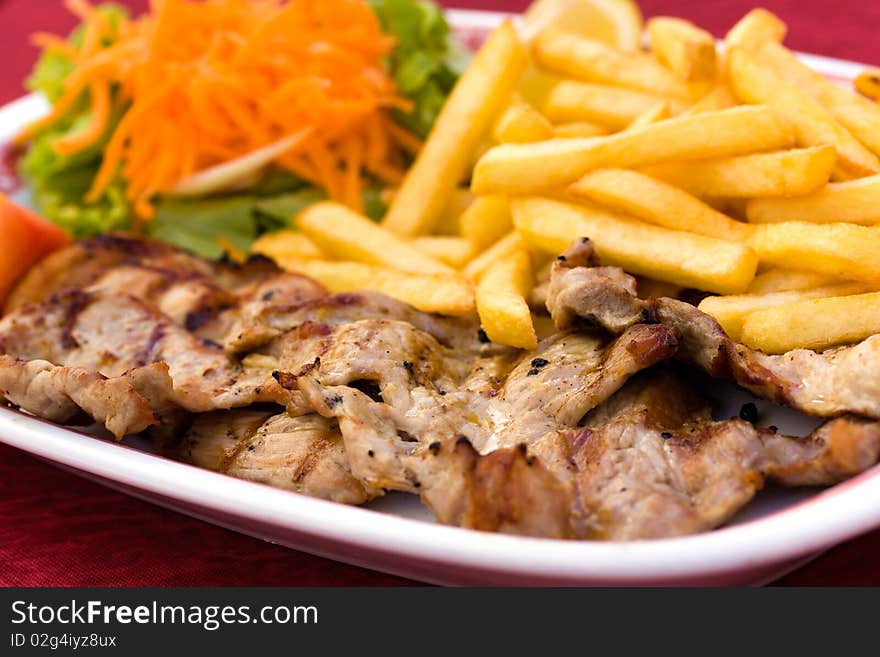 Fresh grilled Pork Chop with french fries and salad of carrot and lettuce